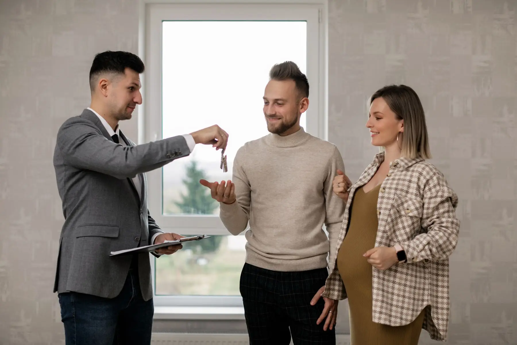 Un agent immobilier tend les clés d'un logement à un jeune couple.