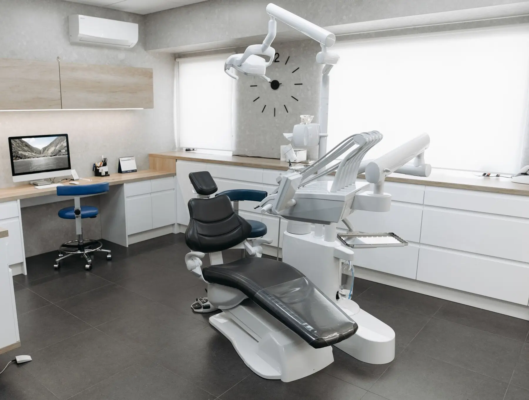 Salle de soins dentaires vide et lumineuse, avec son fauteuil noir sous la lampe.