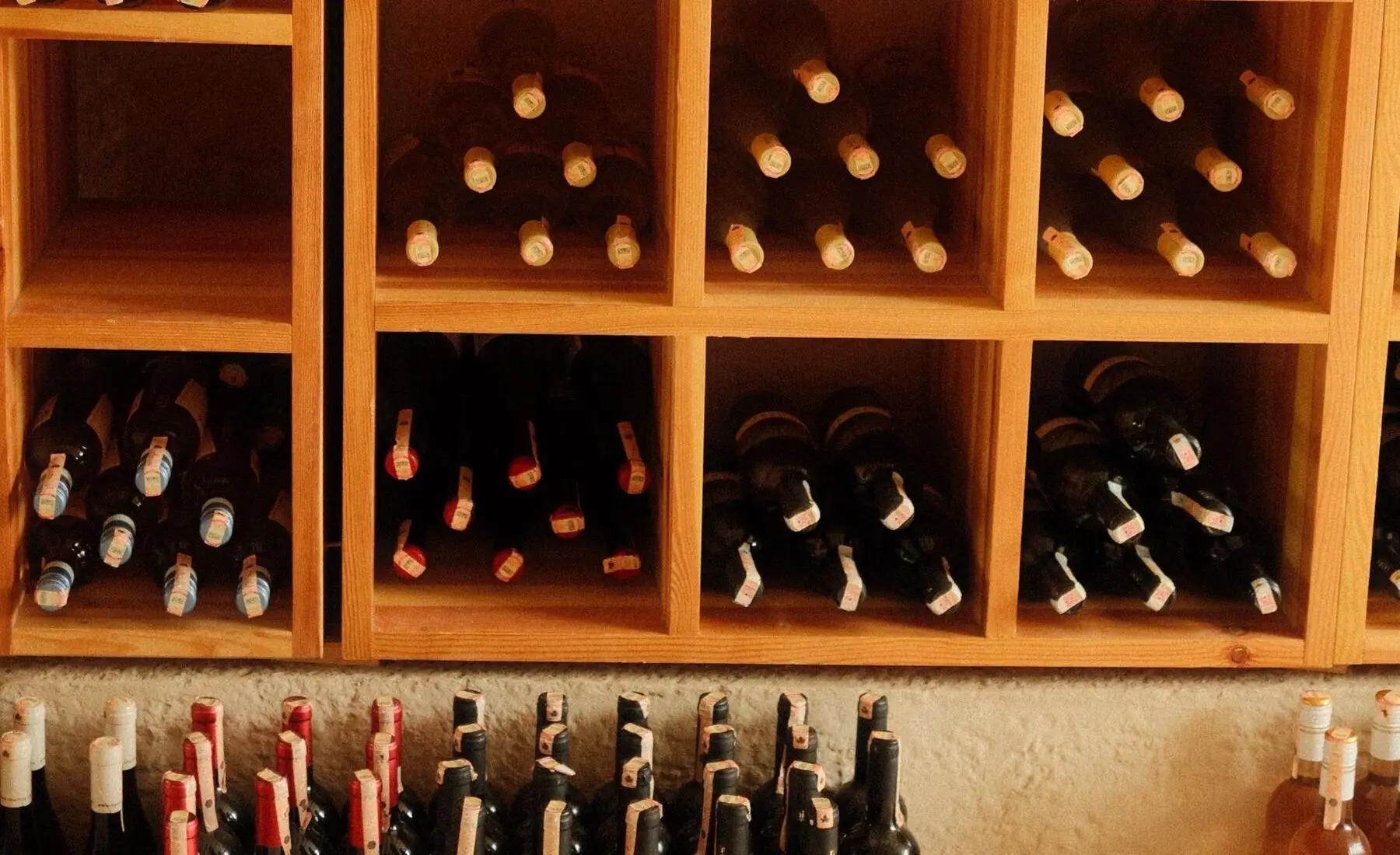 Casiers en bois garnis de bouteilles couchées, dans la boutique d'un caviste.