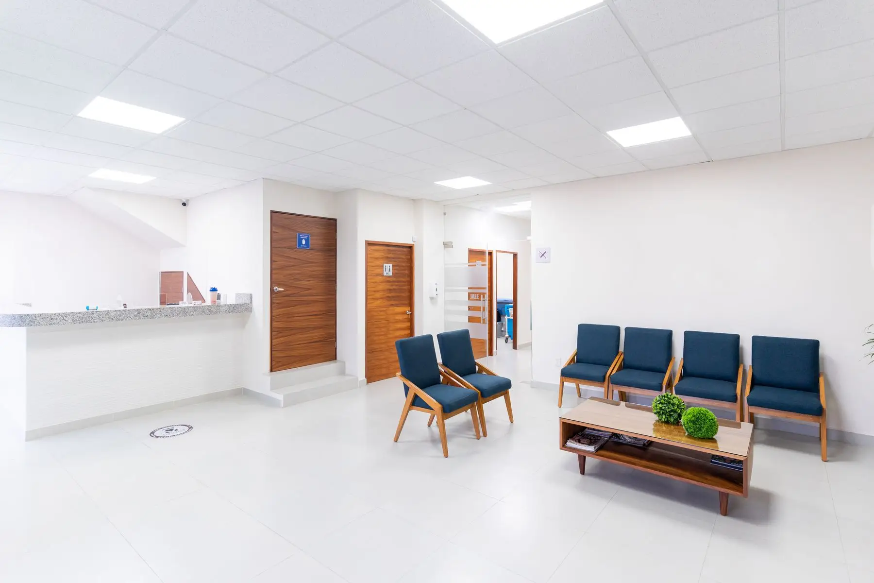 L'accueil vide d'un centre médical, avec son comptoir et des fauteuils bleus.