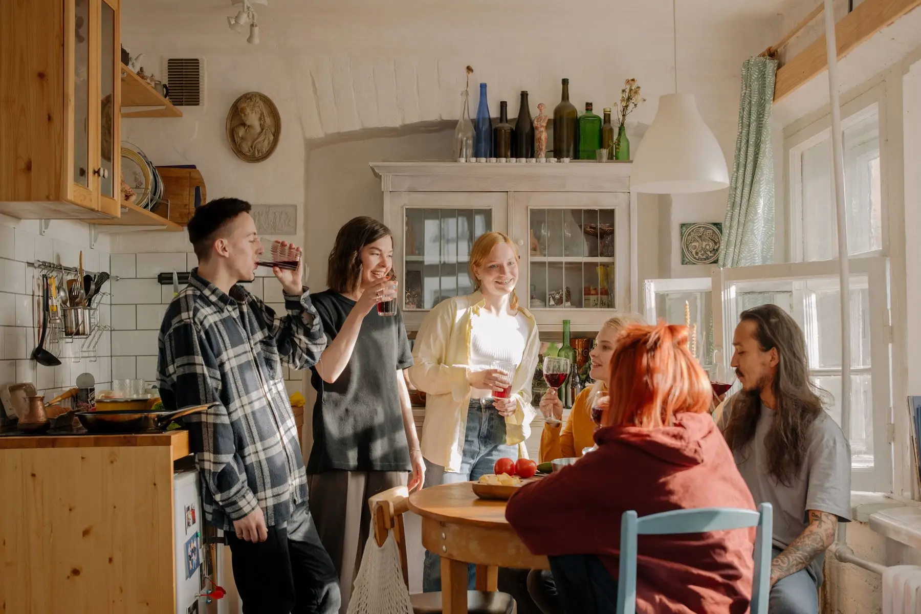 Colocataires réunis autour d'une table dans une cuisine partagée baignée de soleil.