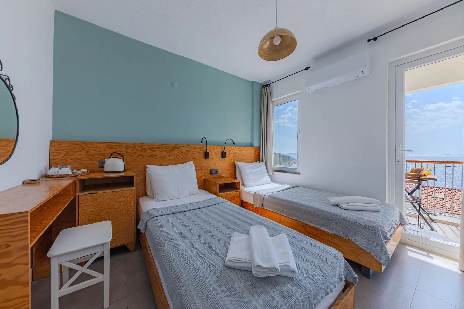 Serviettes pliées sur des lits jumeaux, dans une chambre d'hôtel ouverte sur la mer.