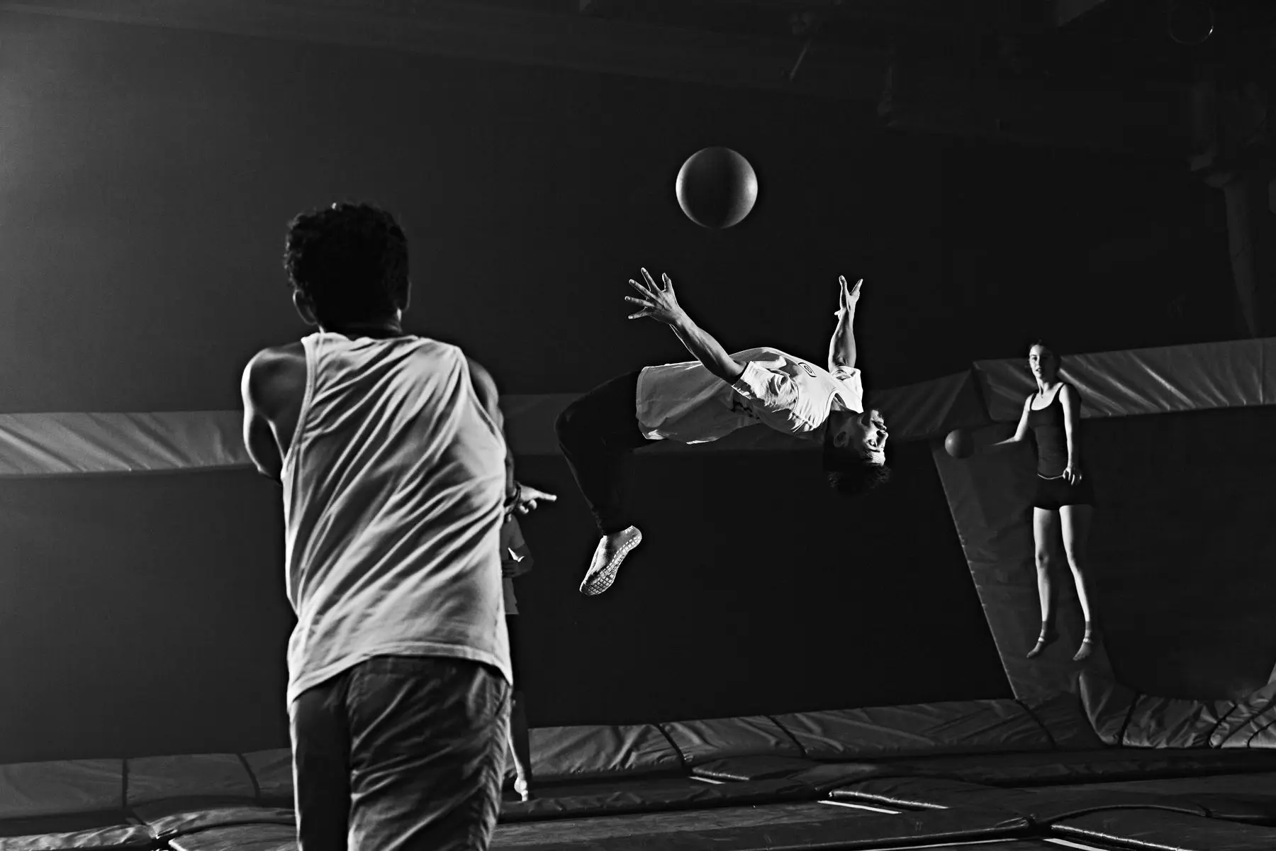 Partie de balle sur trampolines : un joueur fait un salto arrière sous le ballon.